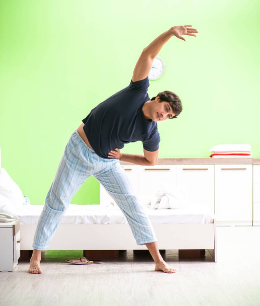 Young man in pajamas doing morning exercises - Photo, Image