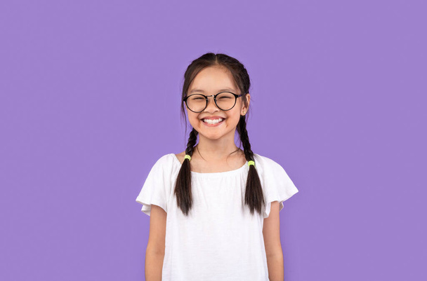 Asiático chico chica usando gafas sonriendo posando sobre púrpura fondo - Foto, imagen