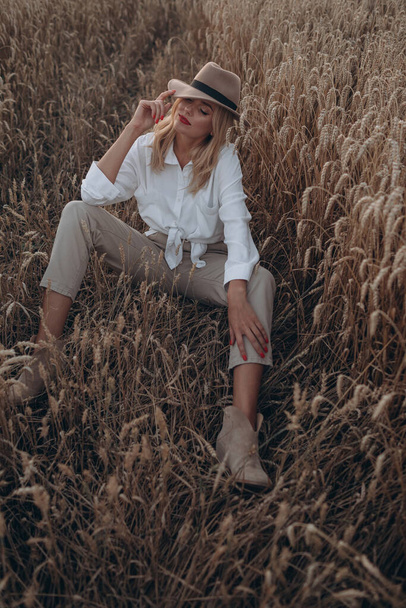 Beautiful blonde woman in a hat in a wheat field - Foto, Imagem