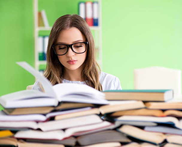 Jonge vrouwelijke student bereidt zich voor op examens met veel boeken - Foto, afbeelding