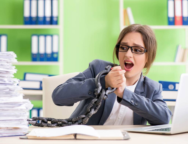Young female employee busy with ongoing paperwork chained to th - Photo, Image