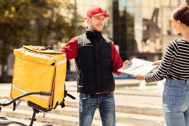 Guy donnant paquet à la fille client debout dans la zone urbaine - Photo, image