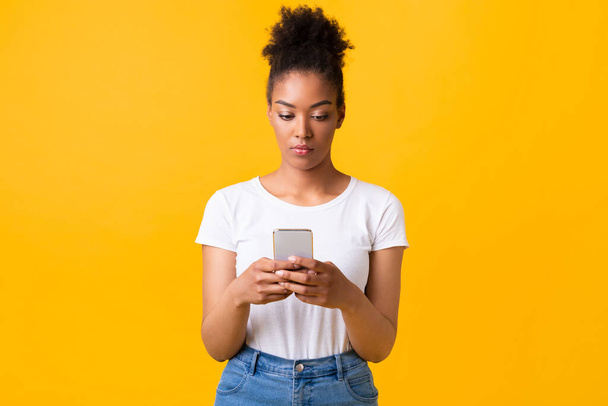 Enfocado afro chica usando el teléfono celular en el estudio - Foto, imagen