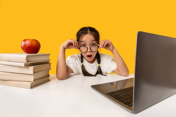 Amazed Schoolgirl Looking At Camera Sitting At Laptop, Yellow Background - Foto, immagini