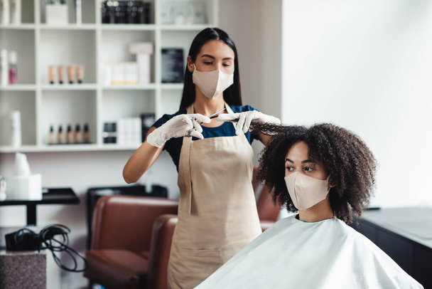 Giovane ragazza nera in maschera protettiva ottenere taglio di capelli al salone, spazio libero - Foto, immagini