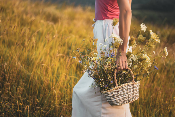Woman walking with basket full of flowers  and enjoys in the nature. - Foto, immagini