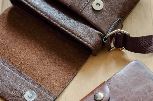 木製のテーブルの上に小さな革袋と財布。バッグと茶色の革財布を開きます。角度でトップビュー。選択的焦点. - 写真・画像