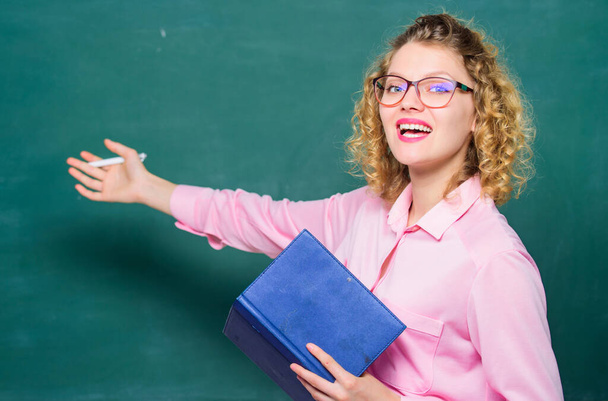 Pedagogue hold book and explaining information. Education concept. Teacher explain hard topic. Woman school teacher in front of chalkboard. Teacher best friend of learners. Passionate about knowledge - 写真・画像