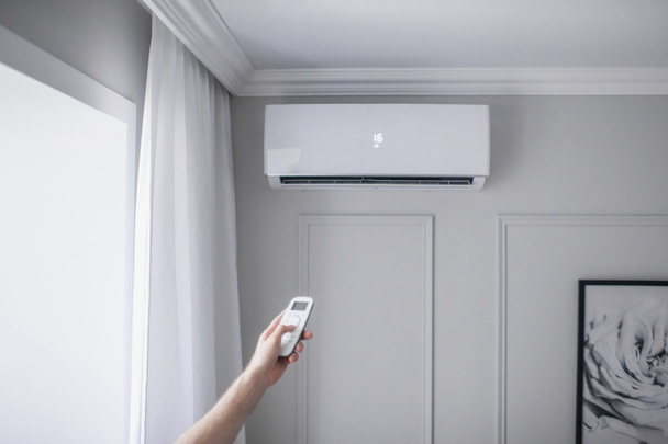 Légkondicionáló a szobában kézi vezérlésű távirányítóval gyönyörű szobában, szürke fal - Fotó, kép
