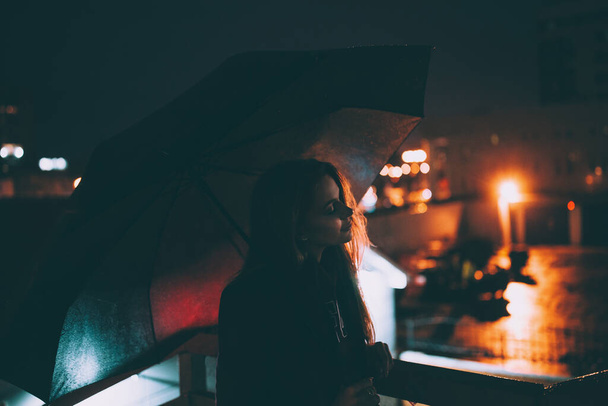 красива молода самотня блондинка, що стоїть біля дороги під парасолькою на нічній вулиці
 - Фото, зображення