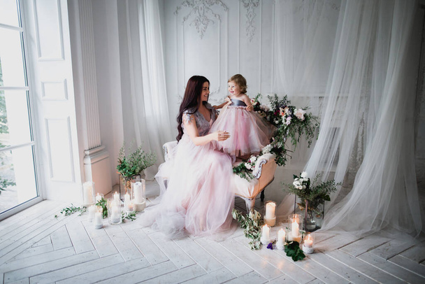 mother and adorable daughter in styling pink dresses in studio - Photo, Image