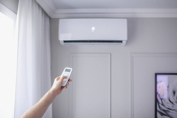 Légkondicionáló a szobában kézi vezérlésű távirányítóval gyönyörű szobában, szürke fal - Fotó, kép