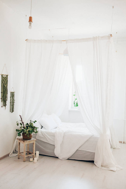 aconchegante quarto leve em um quarto minimalista estilo escandinavo, cama de dossel, travesseiros cobertor, planta. manhã foto ensolarada - Foto, Imagem