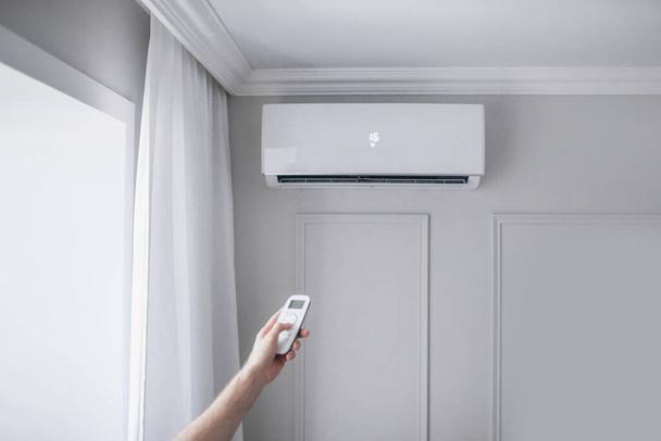 Climatiseur à l'intérieur de la pièce avec télécommande manuelle dans une belle pièce, mur gris - Photo, image