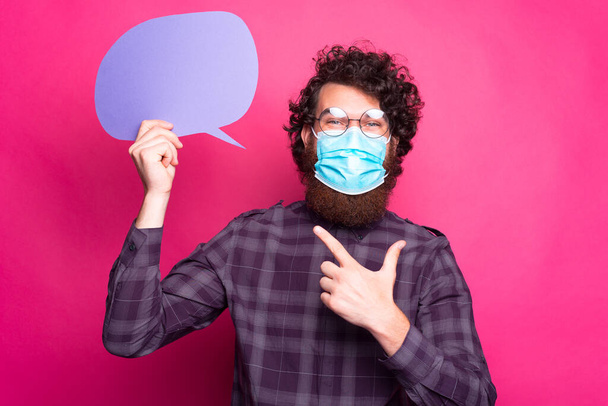 Zdjęcie młodego człowieka noszącego maskę leczniczą i wskazującego na bańkę głosową - Zdjęcie, obraz