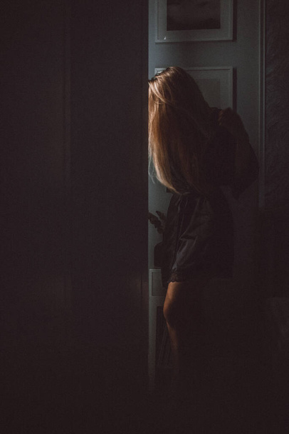 κορίτσι σε ένα μαύρο φόρεμα κοντά στην πόρτα  - Φωτογραφία, εικόνα