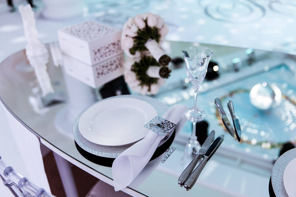 formal de lujo elegante boda decoración restaurante mesas servido mantel blanco, platos, menús, vasos, tulipanes en jarrones, orquídeas, velas sillas de plata, fondo azul - Foto, imagen