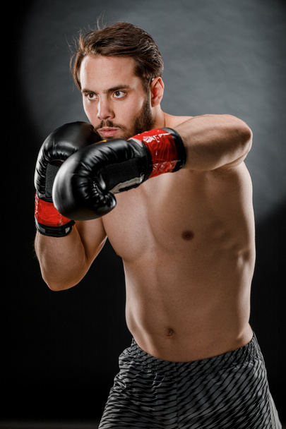 A man in Boxing gloves. A man Boxing on a black background. The concept of a healthy lifestyle. - Photo, Image
