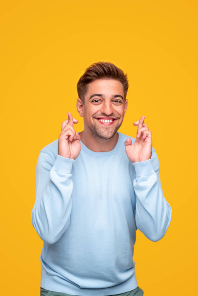 Excited young man with crossed fingers - Foto, Bild