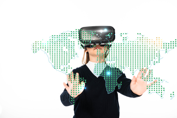 colegiala de pie con las manos extendidas mientras usa auriculares de realidad virtual aislados en blanco, ilustración de mapa global - Foto, Imagen