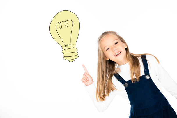 blonde schoolgirl pointing at illustrated light bulb isolated on white - Fotó, kép