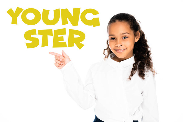 african american schoolgirl pointing with finger at youngster lettering while looking at camera isolated on white - Photo, image