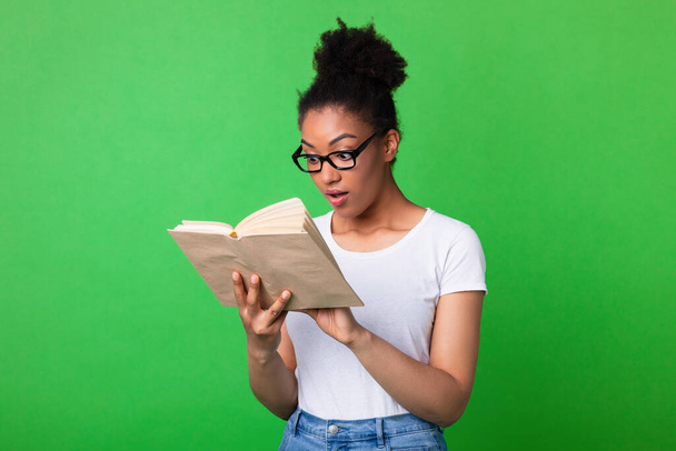 Νεαρή μαύρη κυρία που φοράει γυαλιά διαβάζοντας βιβλίο - Φωτογραφία, εικόνα