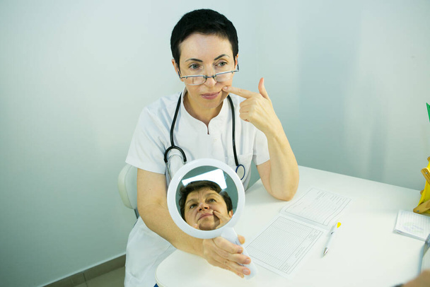 Ein Besuch bei einer Kosmetikerin. Der Arzt erklärt dem Patienten die Notwendigkeit einer Gesichtspflege. - Foto, Bild