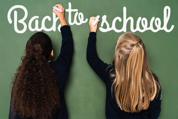 back view of multicultural schoolgirls writing back to school lettering on chalkboard - Zdjęcie, obraz