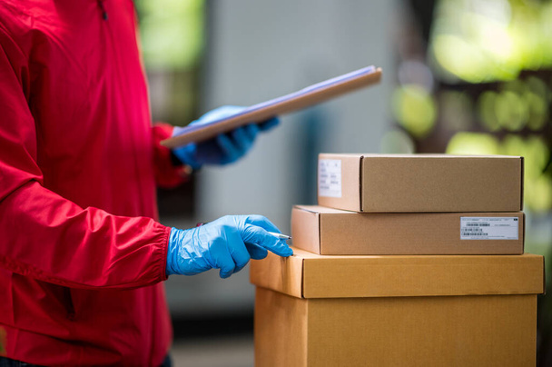 Close up delivery man Wearing blue gloves in red cloth Checking customer boxes for delivery - 写真・画像