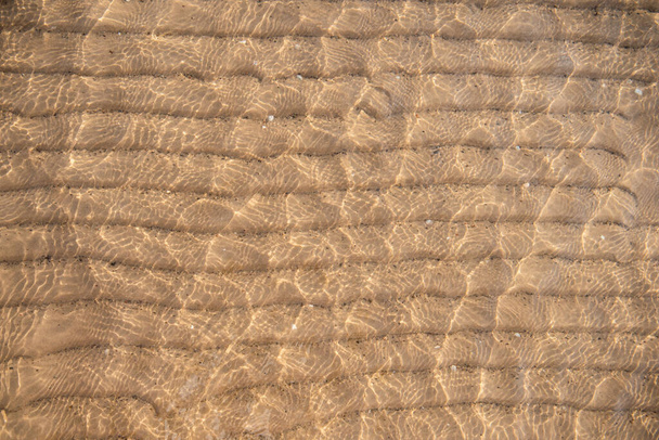 Textura de fondo de arena bajo el agua. Ondulación de agua transparente, olas de arena y resplandor de luz solar. Fondo marino - Foto, imagen