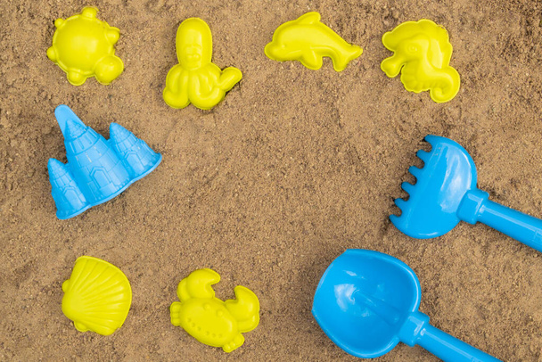 Pelle colorée et râteau et moules dans un bac à sable. Jouets extérieurs en sable pour enfants. Concept d'été. Avec place pour le texte. - Photo, image