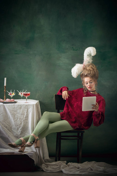 Young woman as Marie Antoinette on dark background. Retro style, comparison of eras concept. - Foto, afbeelding