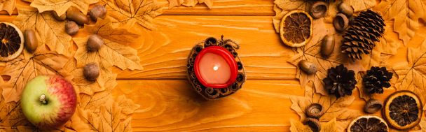 top view of burning candle with autumnal decoration on wooden background - Fotoğraf, Görsel