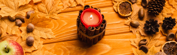hořící svíčka s podzimní výzdobou na dřevěném pozadí, panoramatický záběr - Fotografie, Obrázek
