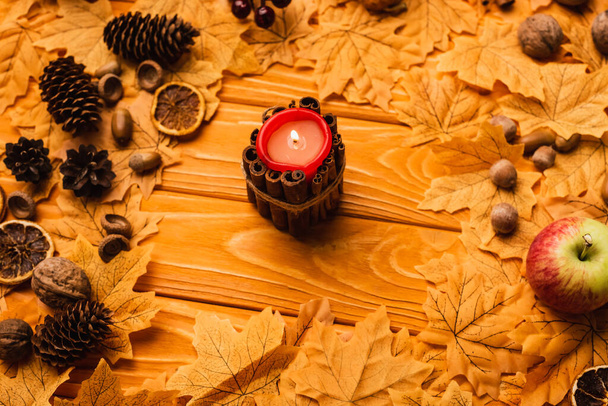 burning candle with autumnal decoration on wooden background - Fotoğraf, Görsel