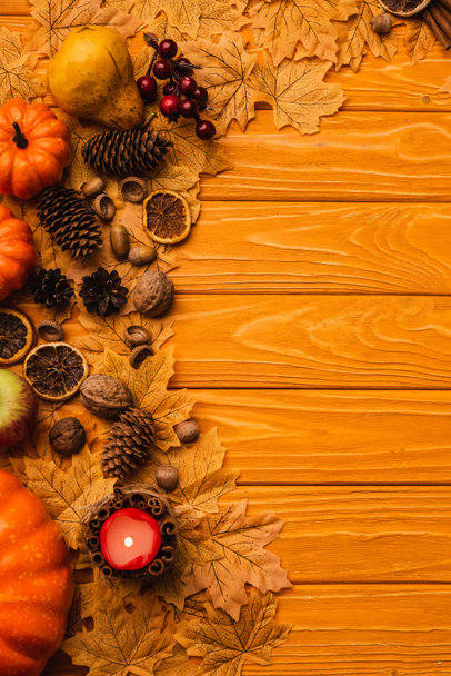 top view of burning candle with autumnal decoration on wooden background - Fotografie, Obrázek