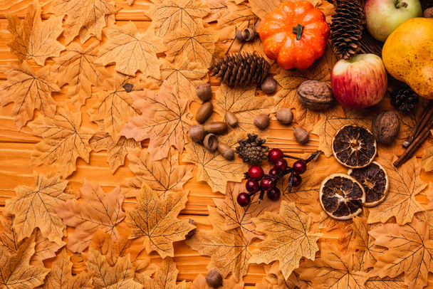 top view of autumnal decoration and food on golden foliage on wooden background - Fotó, kép