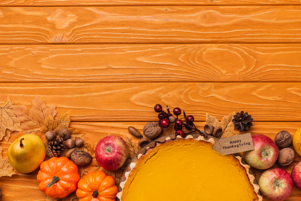 top view of thanksgiving pumpkin pie with autumnal decoration on wooden background - Photo, Image