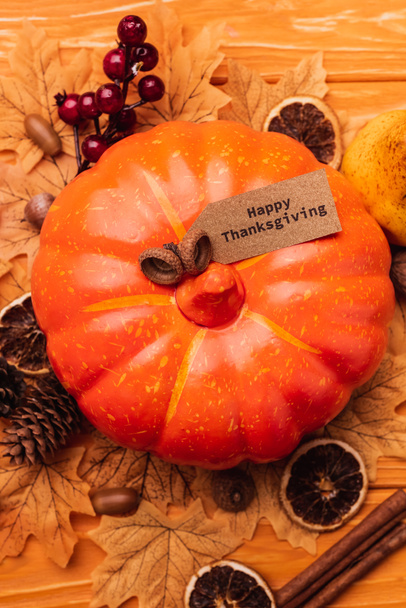 bovenaanzicht van pompoen met herfstdecoratie en gelukkige Thanksgiving kaart op houten achtergrond - Foto, afbeelding