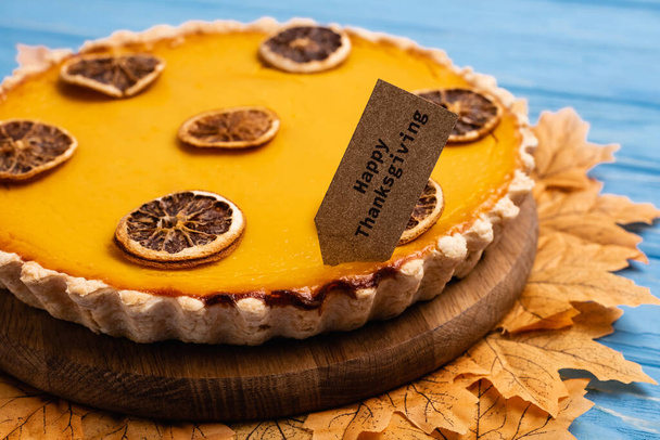 close up view of decorated pumpkin pie with happy thanksgiving card - Фото, изображение