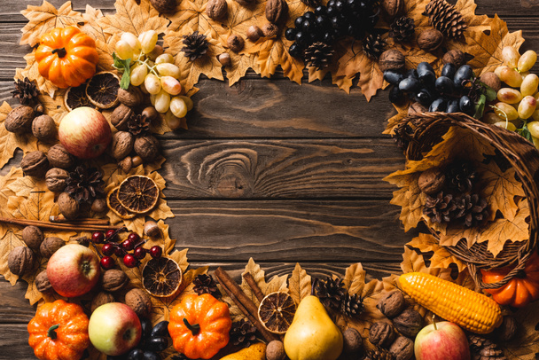 top view of round frame made of autumnal harvest and foliage on brown wooden background - Fotó, kép