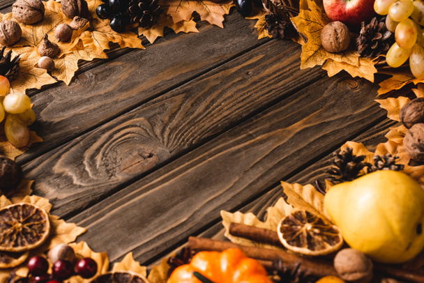 round framer of autumnal decoration on brown wooden background - 写真・画像