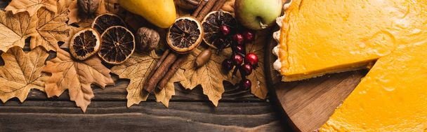vrchní pohled na podzimní dekoraci a dýňový koláč na hnědém dřevěném pozadí, panoramatický záběr - Fotografie, Obrázek