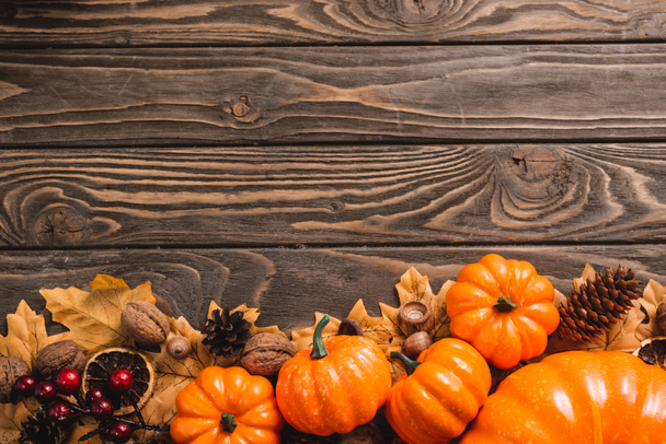 top view of autumnal decoration and pumpkins on brown wooden background - Фото, изображение
