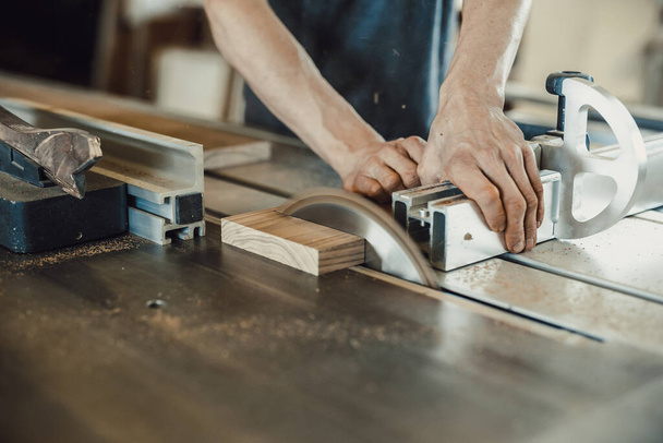 A carpenter cutting a piece of wood with a machine - Фото, зображення