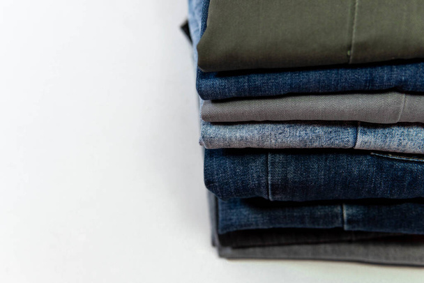 A stack of neatly folded jeans on white background - Photo, Image