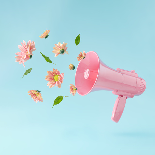 Pinkfarbenes Megafon mit bunten Sommerblumen und grünen Blättern vor pastellblauem Hintergrund. Werbeidee. Minimales Naturkonzept. - Foto, Bild