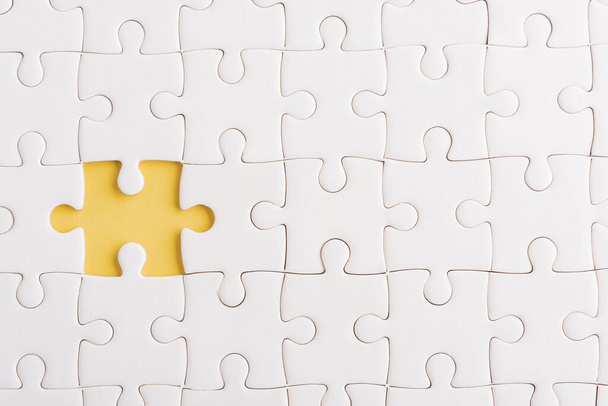 Top view flat lay of paper plain white jigsaw puzzle game texture incomplete or missing piece, studio shot on a yellow background, quiz calculation concept - Photo, image