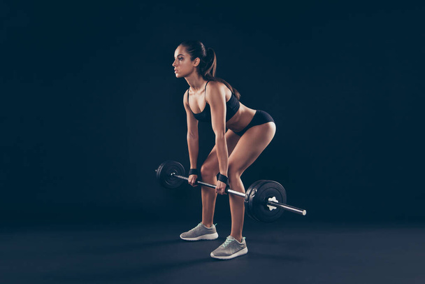 Full length profile photo short sport suit lady heavy barbell hands serious try hard bending spine isolated black background - Φωτογραφία, εικόνα